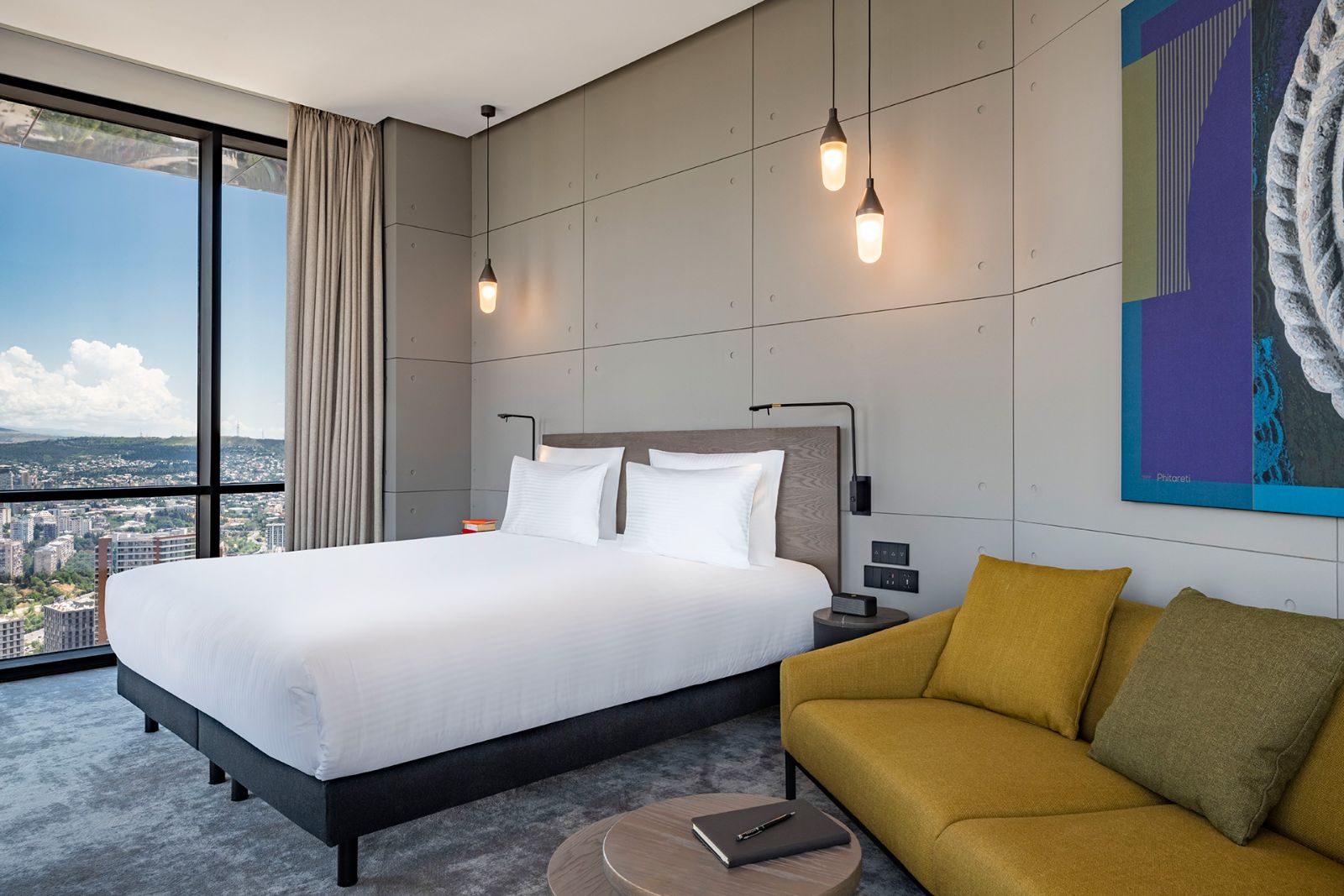 Junior Suite with a king bed and yellow sofa, Pullman Tbilisi Axis Towers