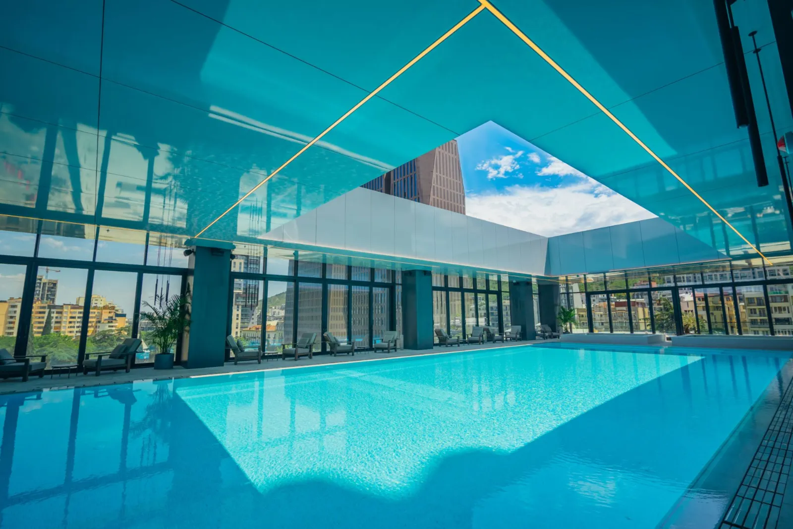 A guest swimming in the 25-metre indoor pool, city towers through the glass