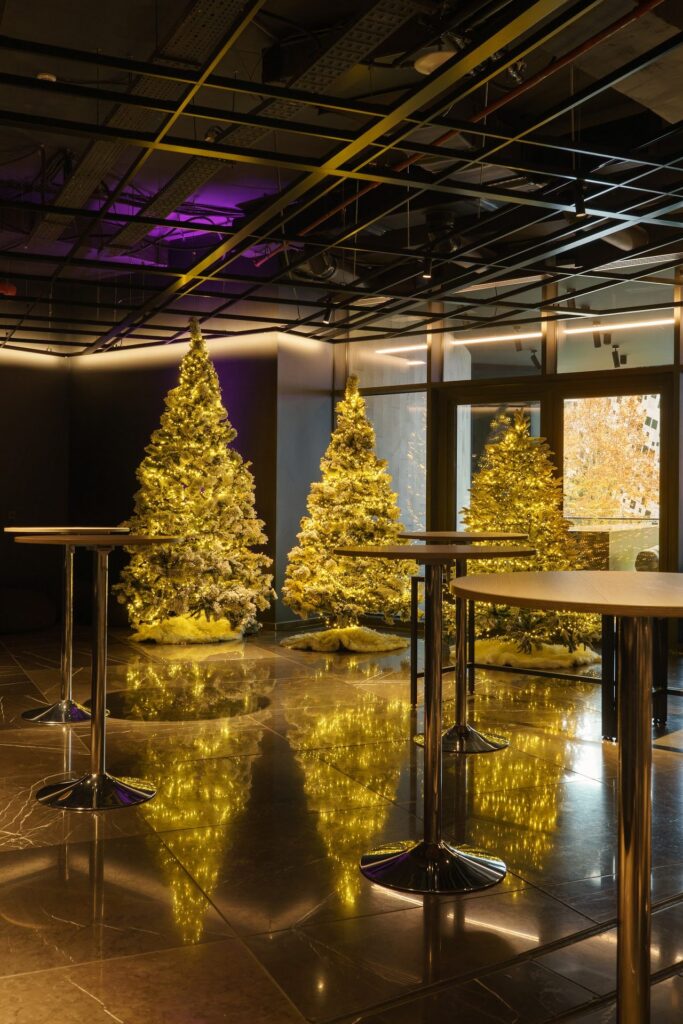 Golden Christmas trees reflected on a dark marble floor at Pullman Tbilisi